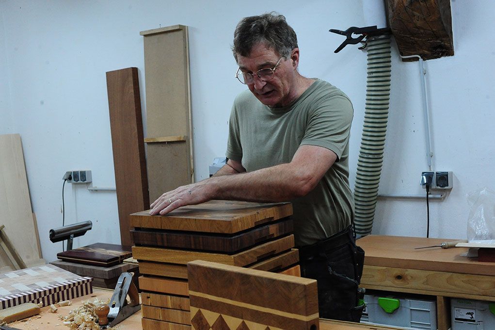 Ein Mann arbeitet in einer Werkstatt an einem Stapel Holzklötze.