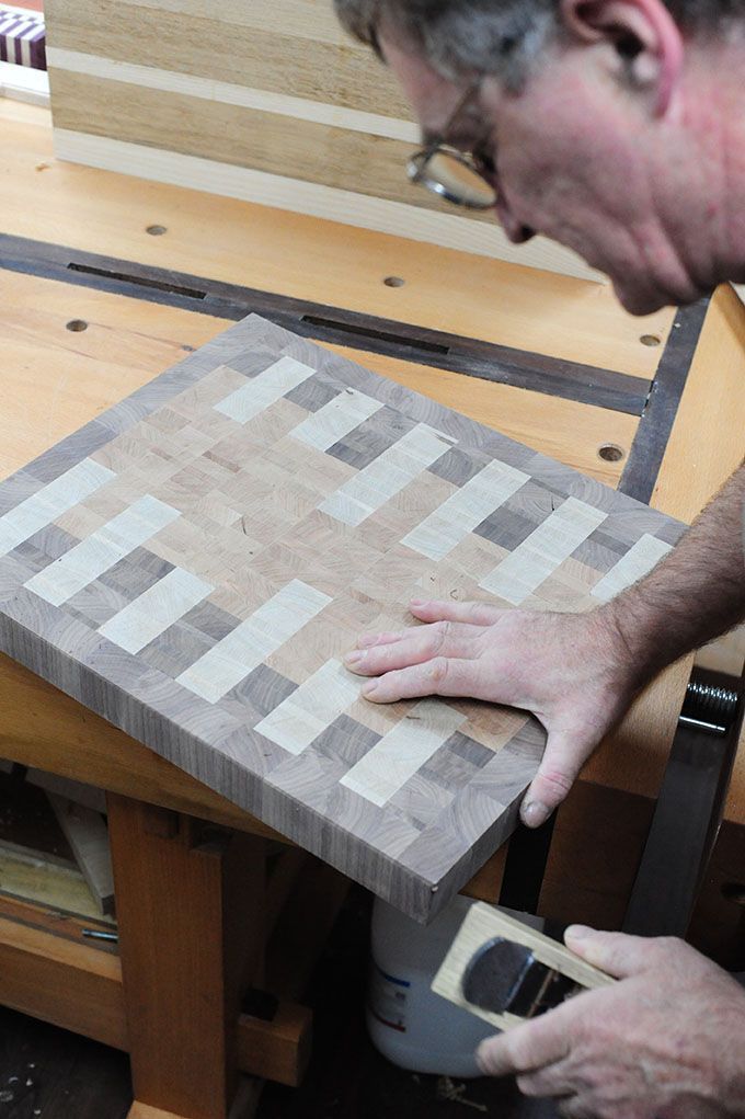 Ein Mann misst ein Stück Holz auf einer Werkbank.