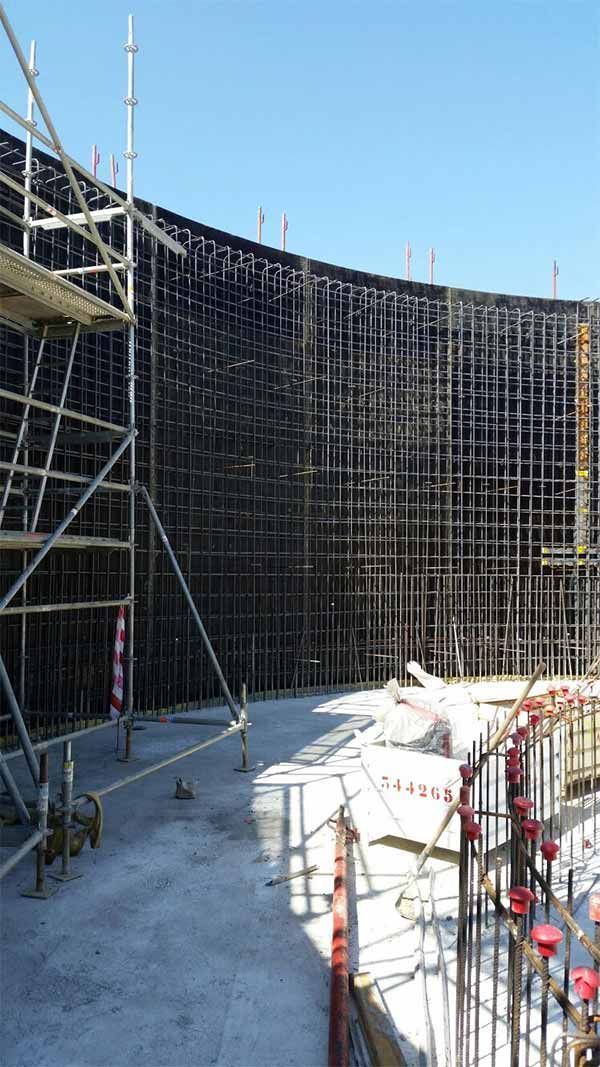 Un gran edificio en construcción con andamios y un cielo azul al fondo.