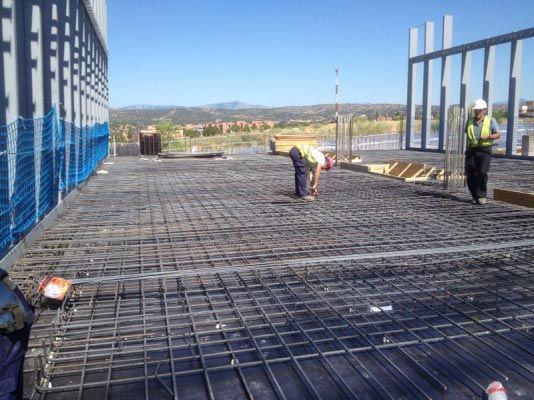 Un grupo de trabajadores de la construcción está trabajando en un piso de concreto.