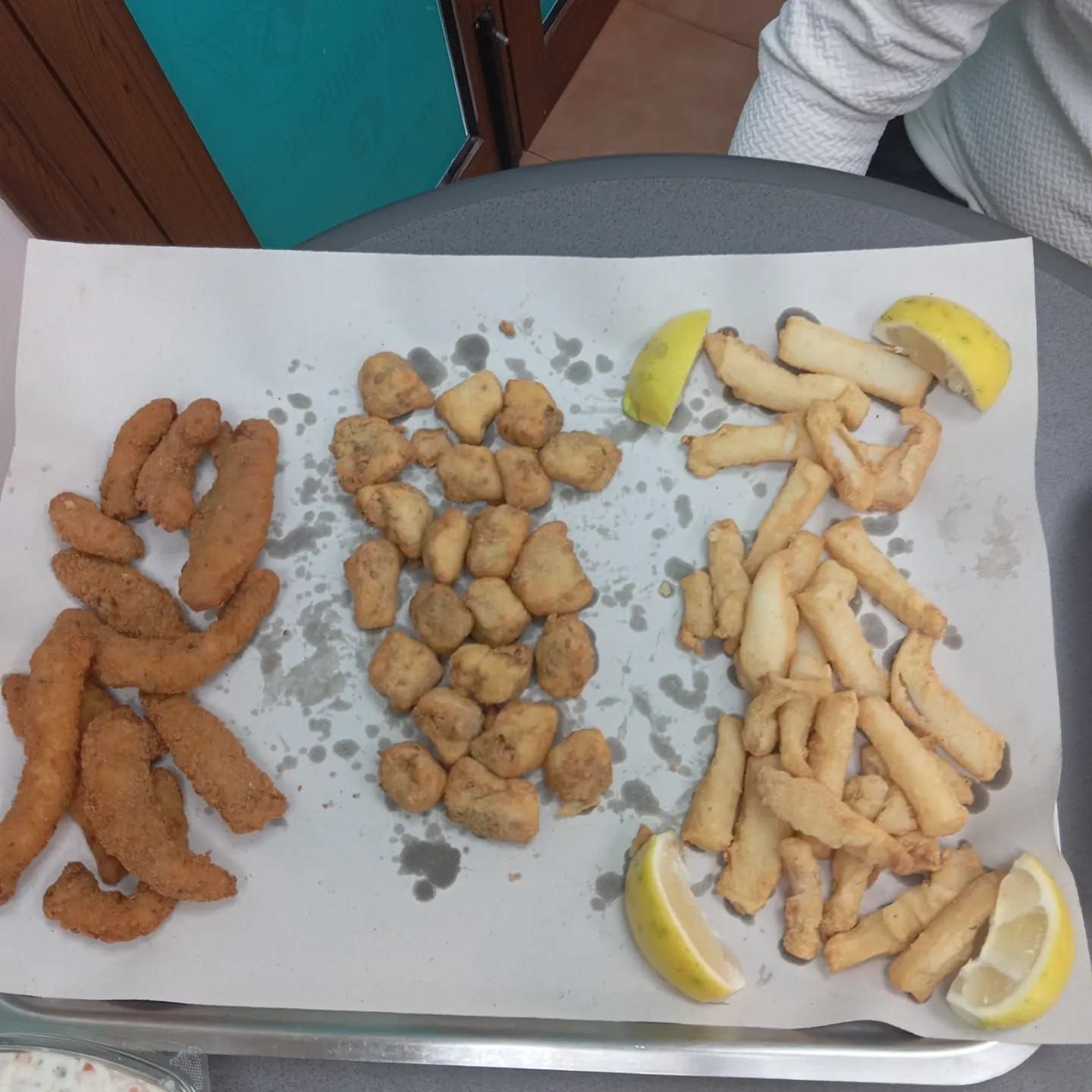 Plato de mariscos fritos con rodajas de limón sobre papel blanco.