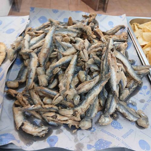 Pila de anchoas fritas sobre papel estampado de color azul.