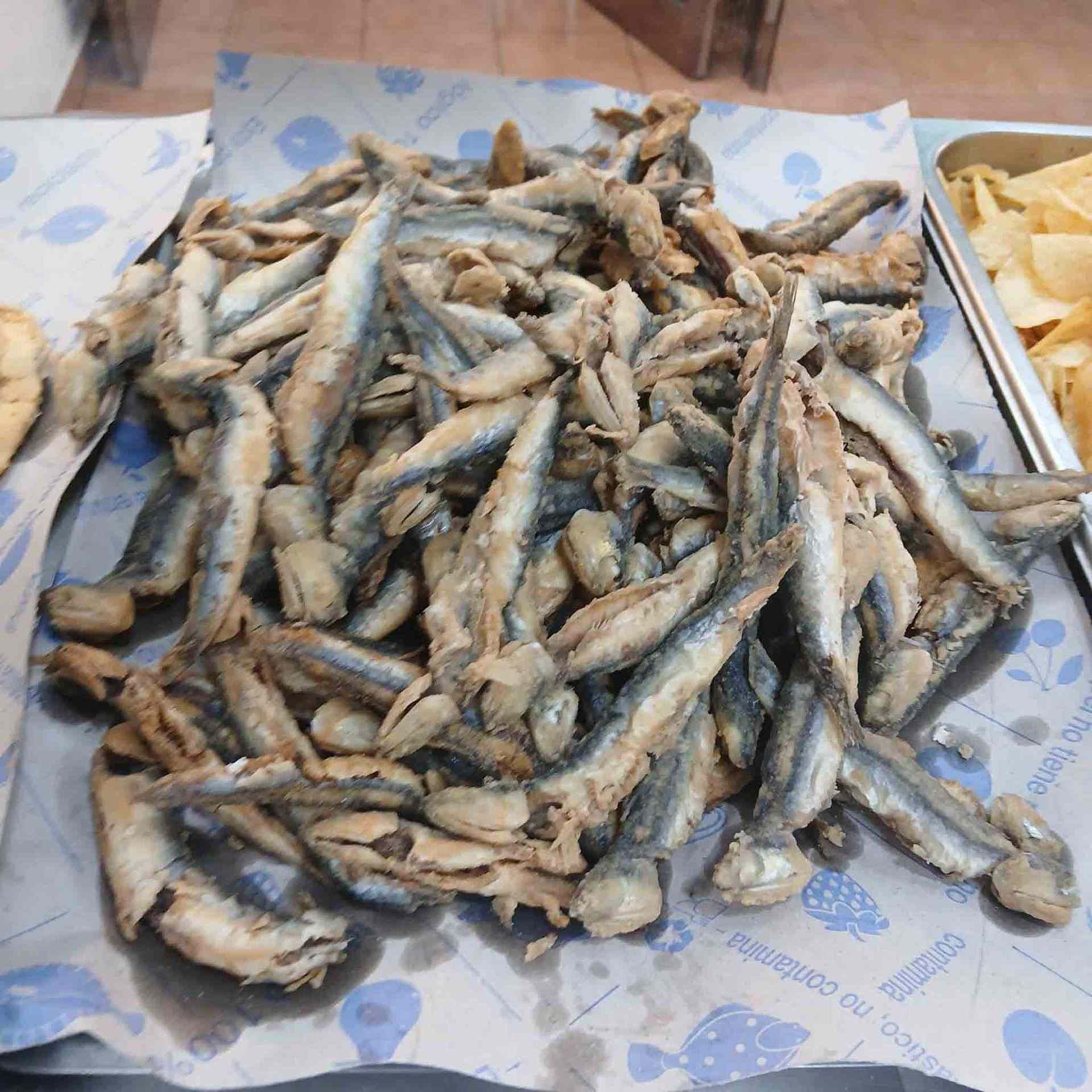 Pila de anchoas fritas sobre papel estampado de color azul.