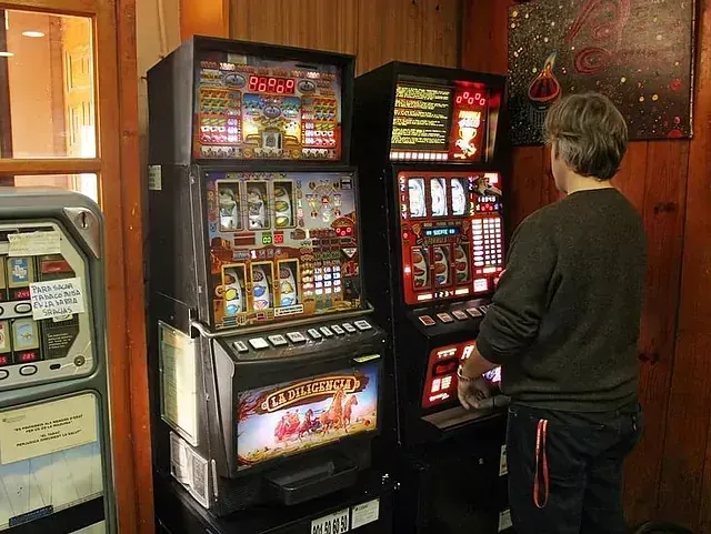 Un hombre está jugando a una máquina tragamonedas en una habitación.