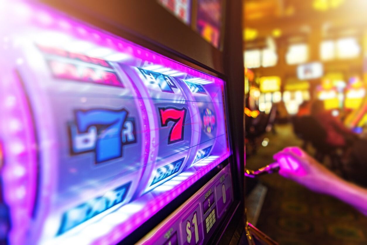 Una persona está jugando en una máquina tragamonedas en un casino.