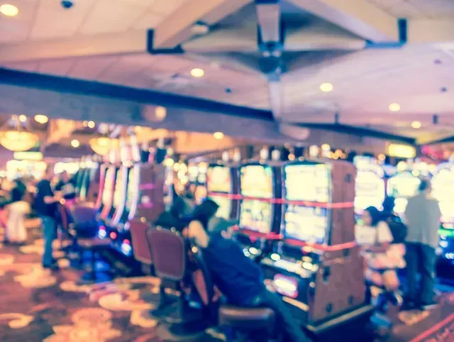 Una imagen borrosa de personas jugando a las máquinas tragamonedas en un casino.