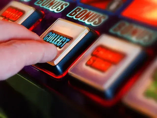 Una persona está presionando el botón de cobrar en una máquina tragamonedas.
