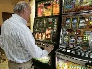Un hombre está jugando en una máquina tragamonedas en un casino.