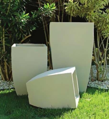 Tres jardineras blancas se encuentran sobre un exuberante césped verde.