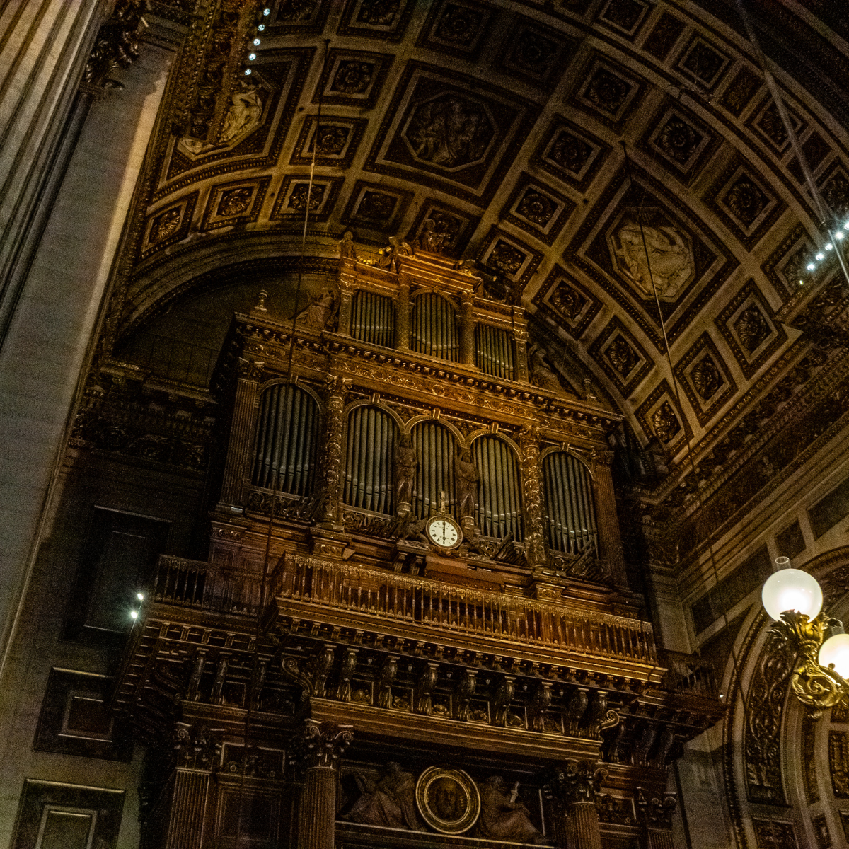 Narrow Parisian street lined with tall, cream-colored buildings. Street slopes downward; pedestrians and shops visible. 