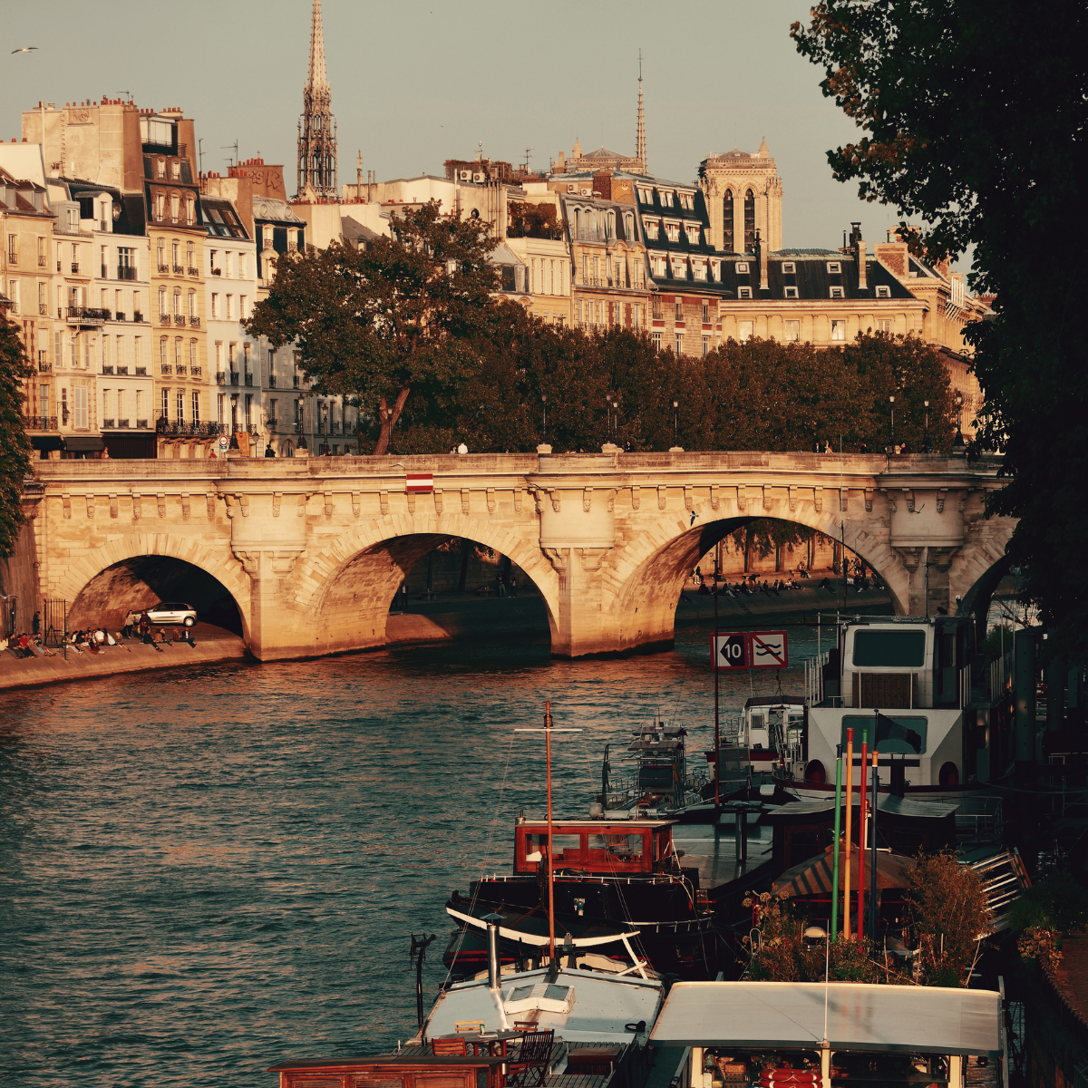 Woman wearing headset at desk with computer, Eiffel Tower art in background.