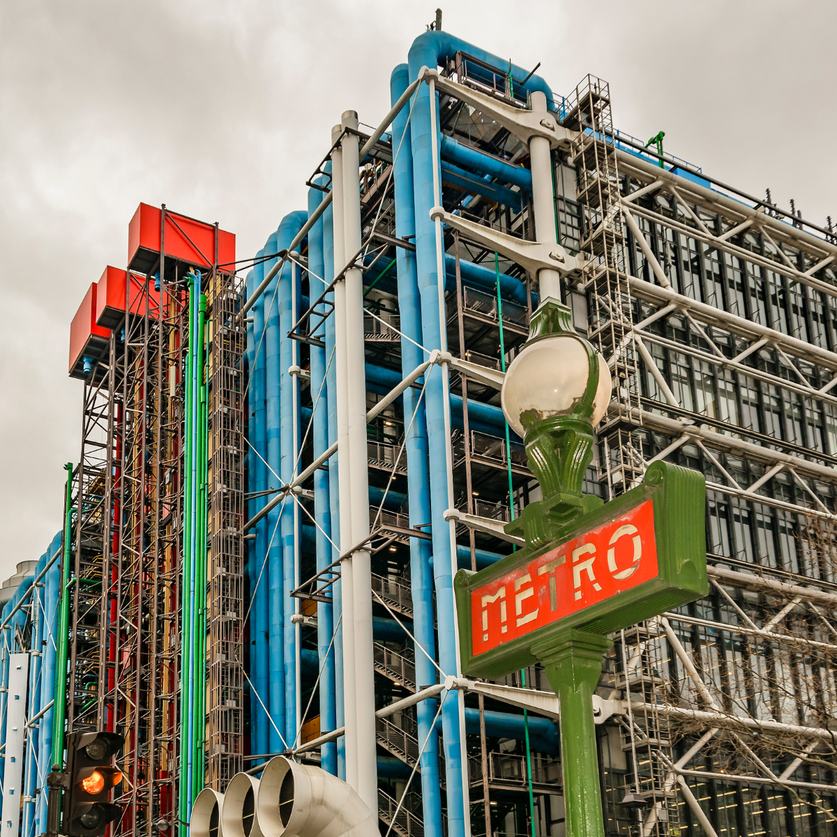 Narrow Parisian street lined with tall, cream-colored buildings. Street slopes downward; pedestrians and shops visible. 