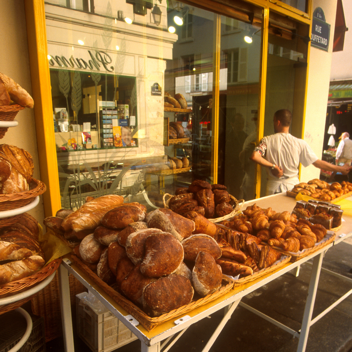 Woman wearing headset at desk with computer, Eiffel Tower art in background.