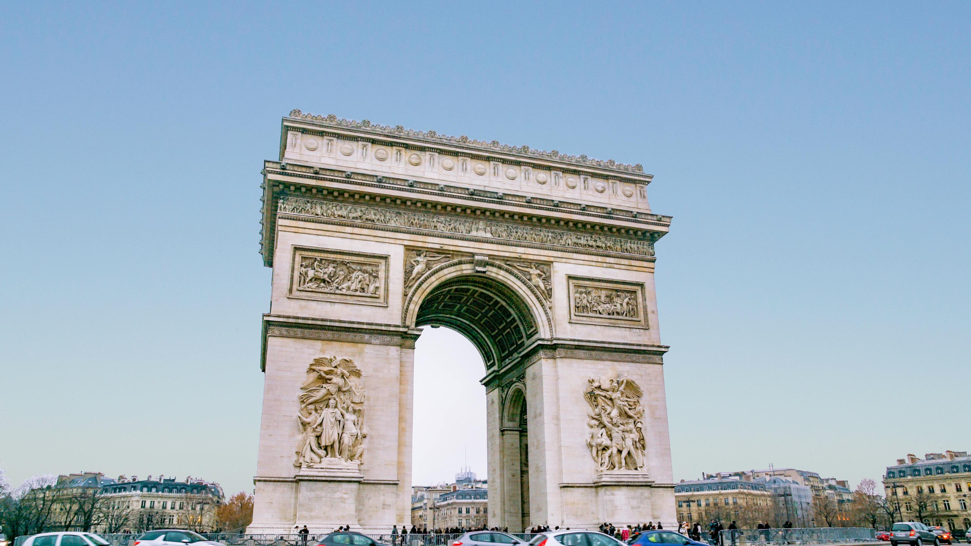 Arc de Triomphe in Paris, France, with blue sky and buildings in background.