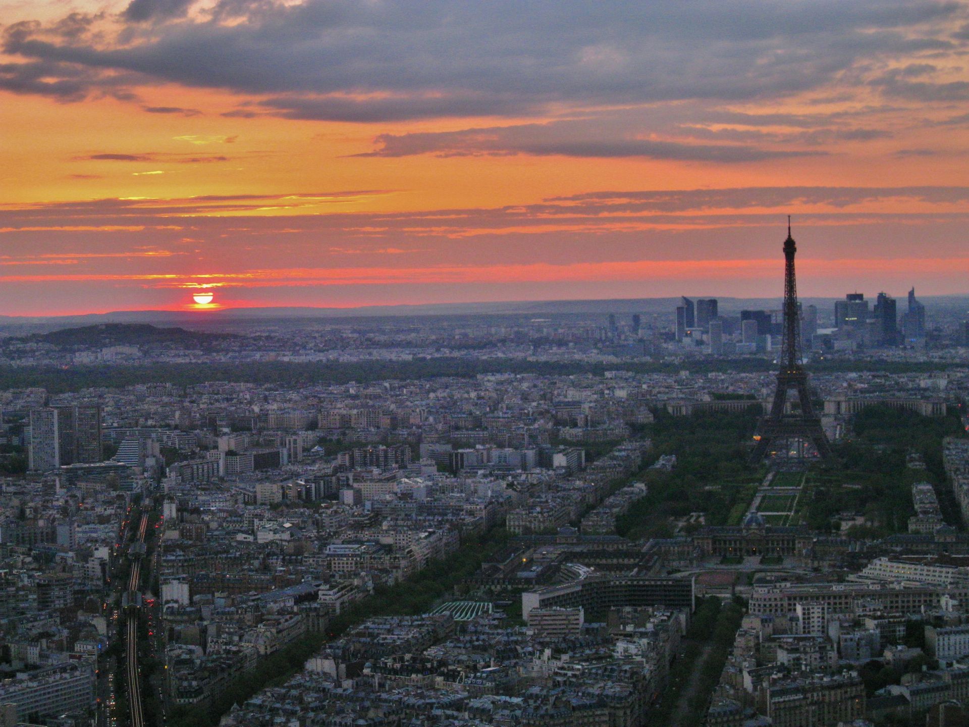 Paris at sunset: Eiffel Tower silhouetted against a vibrant orange sky over a cityscape.