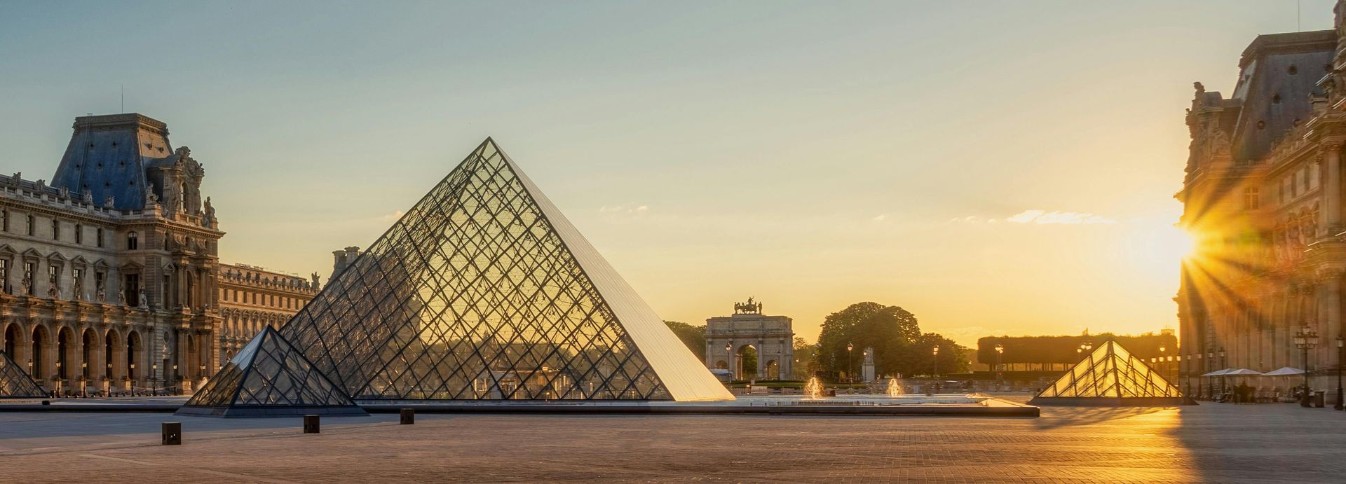 Louvre Pyramid at sunset with the sunbursting through the building.