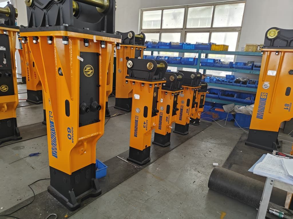 Maquinaria industrial naranja con bases negras alineada en un taller o fábrica.