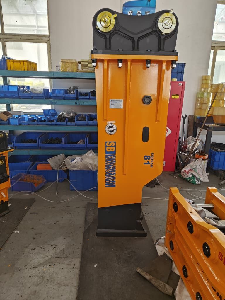 Máquina industrial naranja en un taller, con estanterías y herramientas azules al fondo.