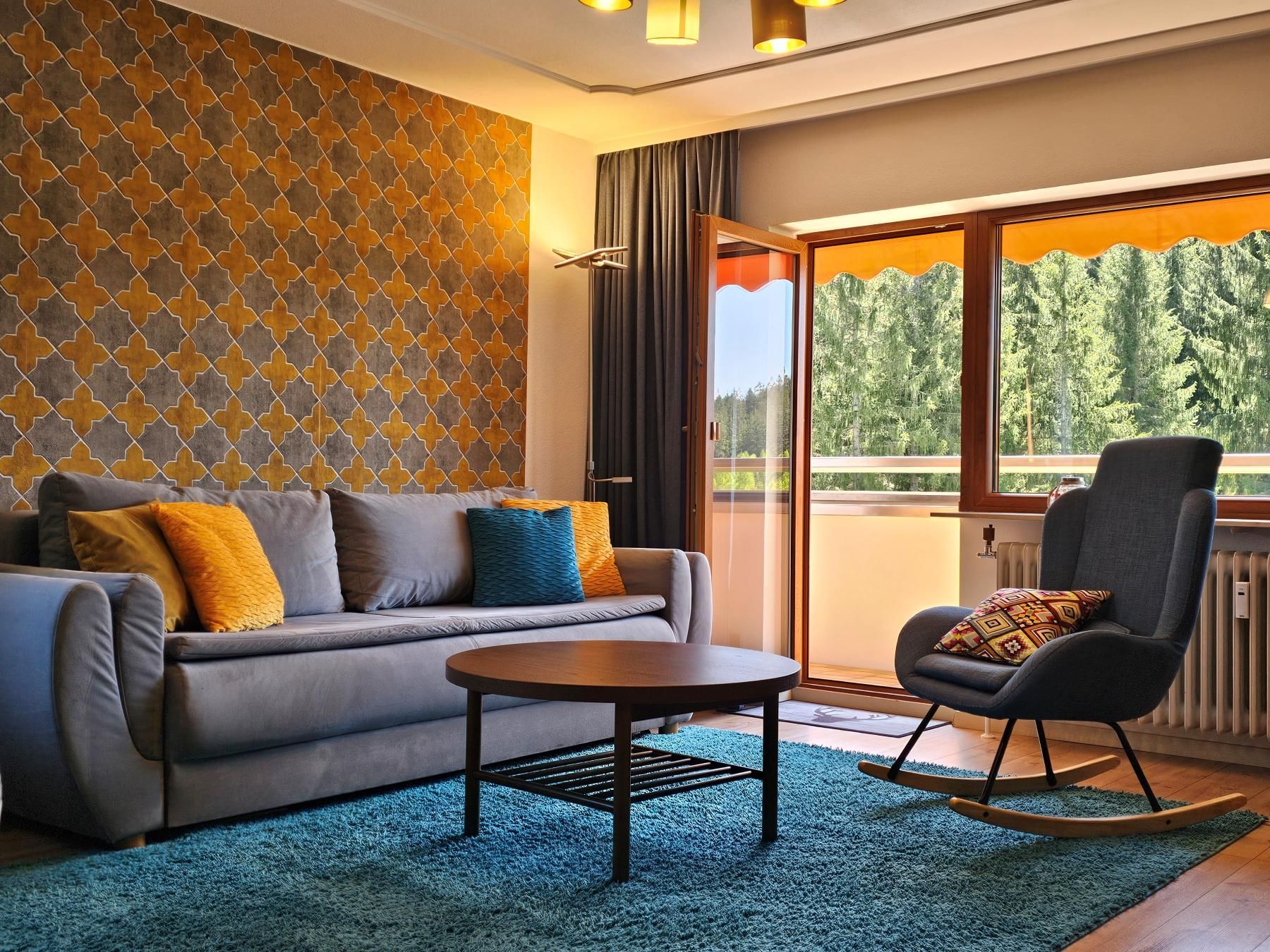 Ferienwohnung Tannenballett mit separatem Schlafzimmer und Schwarzwaldpanorama Wohnzimmer der Ferienwohnung Tannenballett mit Sofa, Sessel und Balkonzugang im Schwarzwald