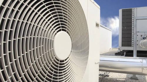 Unité de climatisation blanche sur un toit, avec un ciel bleu en arrière-plan.