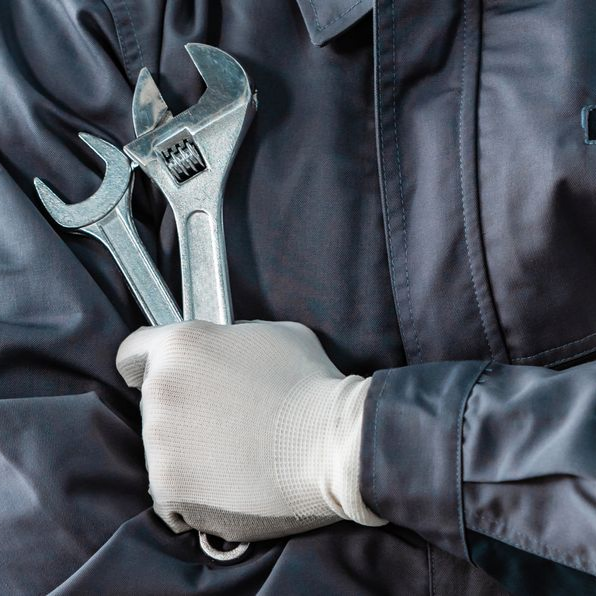 Mécanicien en uniforme gris, main gantée tenant deux clés.