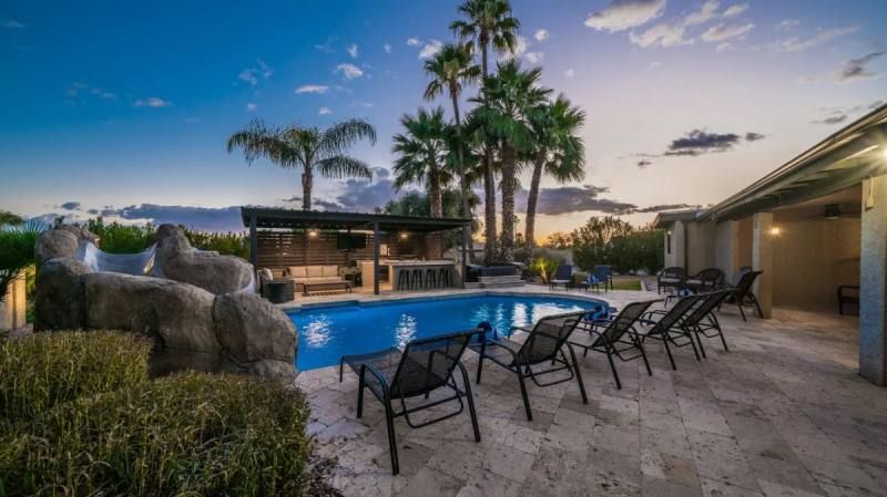 Pool area with loungers, bar, slide, and palm trees at dusk.