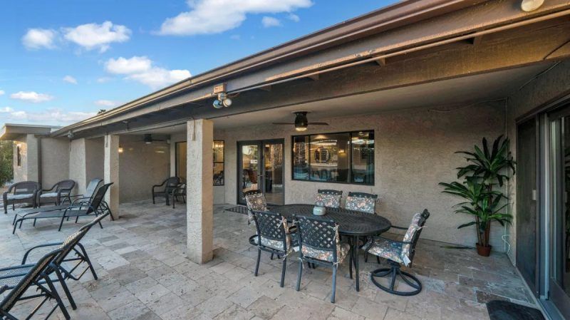 Patio with outdoor furniture under a covered area, sunny day.