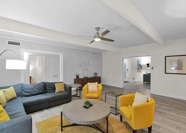 Living room with blue sectional, yellow chairs, gray coffee table, and hardwood floors.