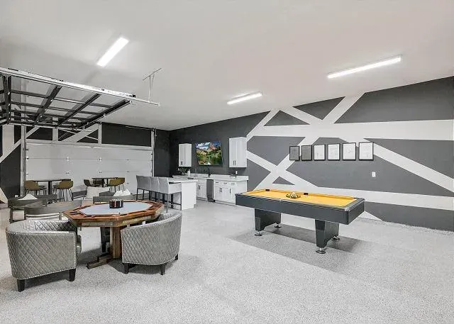 Spacious, remodeled garage interior with poker table, air hockey, bar seating, and gray and white geometric accent wall.
