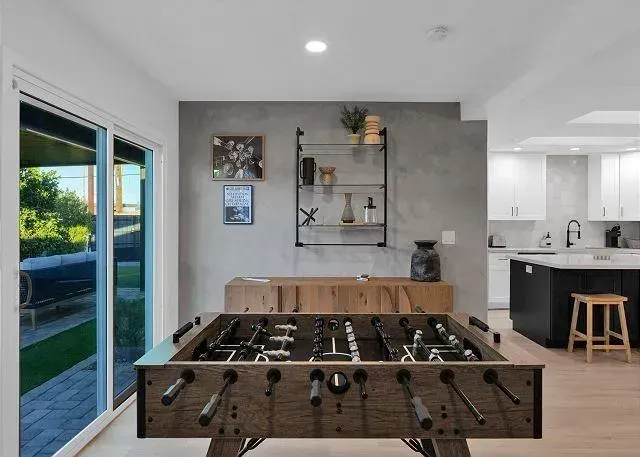 Foosball table in a room with a concrete accent wall and a view of a backyard.