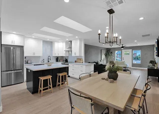 Modern kitchen with white cabinets, black island, and dining table.