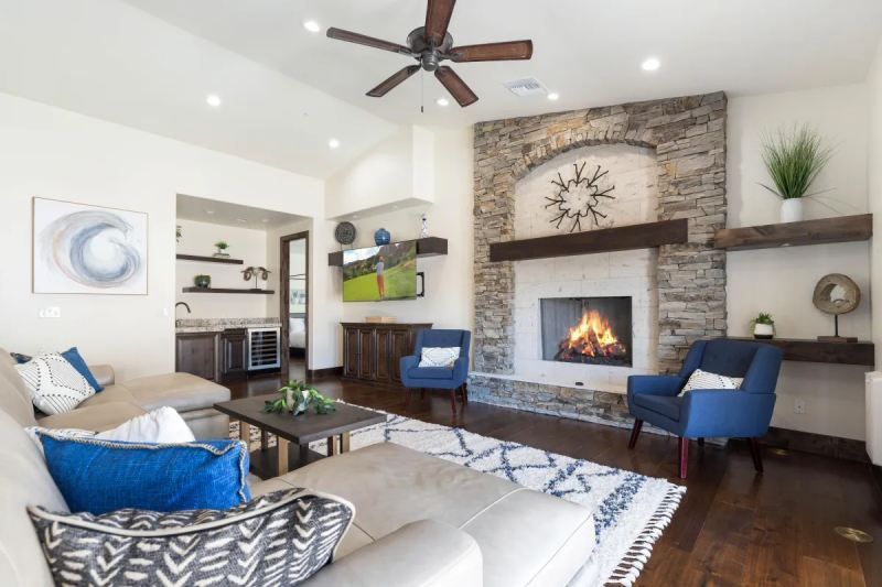 Living room with a fireplace, sofa, chairs, and bar area. Brown, blue, and white colors.