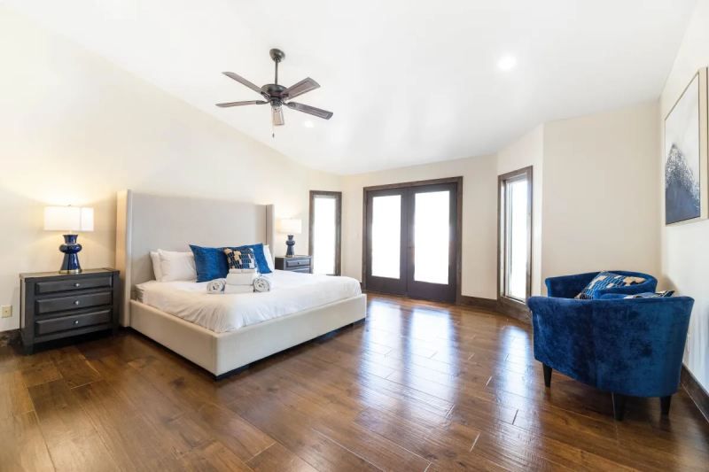 Spacious bedroom with a king bed, blue accents, hardwood floors, and French doors.