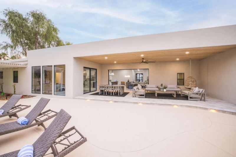 Patio with lounge chairs, outdoor dining, and living area under a covered space with a view of a modern home.