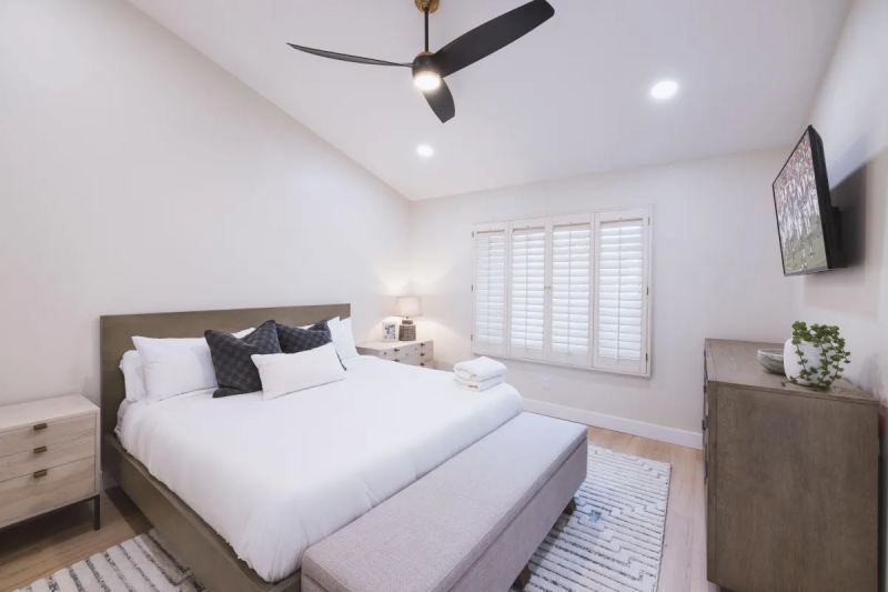 Bedroom with white walls, bed, nightstands, and a ceiling fan.