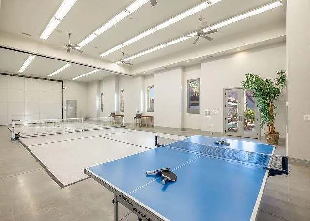 Large, bright room with ping pong table, overhead lights, and a retractable screen.