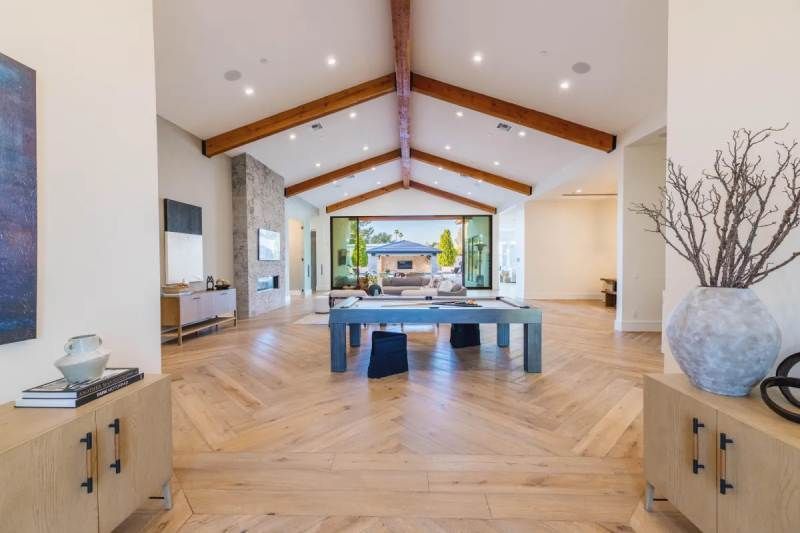 Spacious modern living room with wood floors, exposed beams, and open doors to patio.