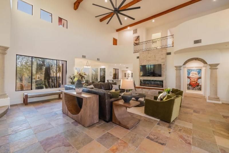Spacious living room with high ceilings, fireplace, and large windows overlooking trees.