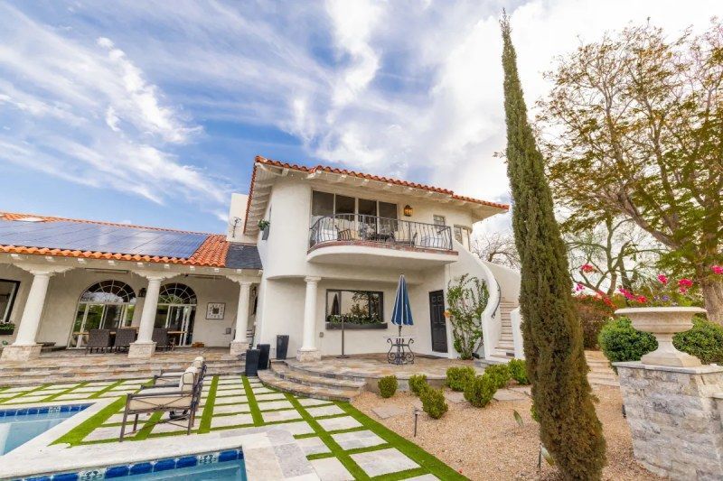White two-story house with a pool, patio, and blue sky.