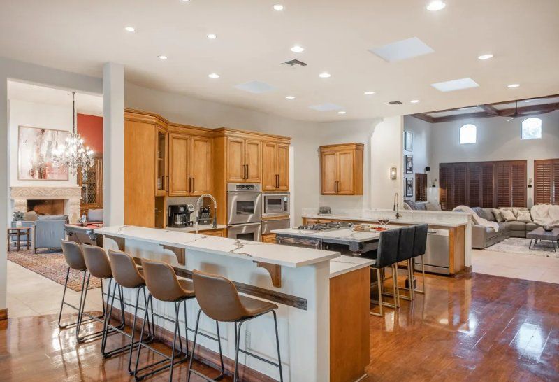 Spacious kitchen with wood cabinets, center island, bar seating, and open to a living area with fireplace.