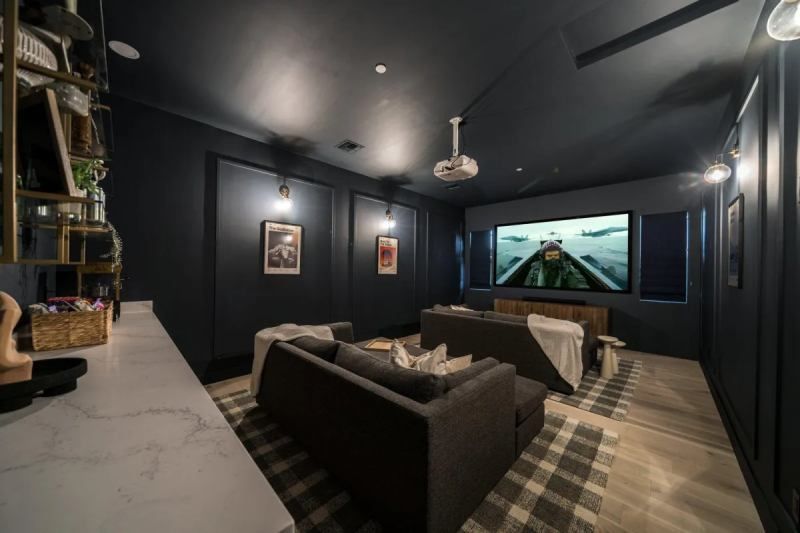 Dark blue home theater with couches, projector screen, and artwork.