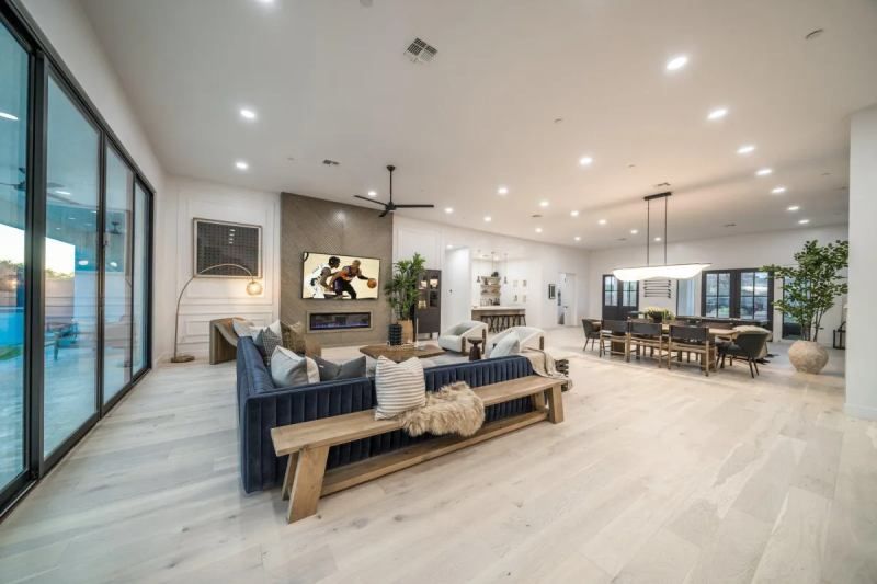 Spacious modern living room with large windows, blue sofa, and open dining area.