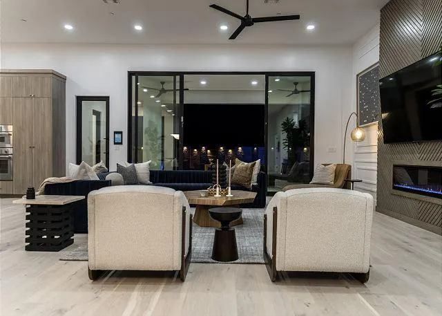 Modern living room with light wood floors, a fireplace, and large sliding glass doors.