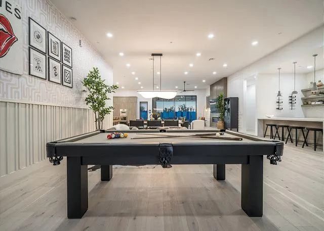 Pool table in a bright modern room with a bar and Rolling Stones artwork.