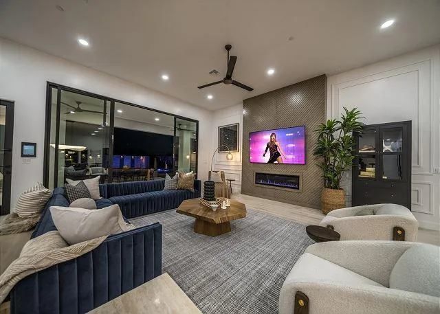 Living room with blue sofa, large TV over fireplace, and glass doors to a dark patio.