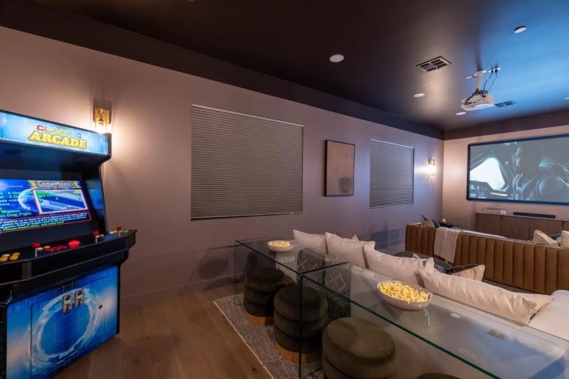 Arcade and home theater room with popcorn, seating, and screen.