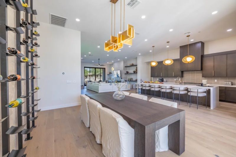 Modern kitchen and dining area with wine rack and long table set for dining.