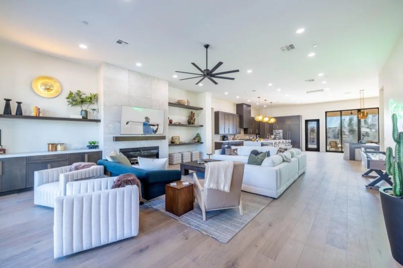 Spacious modern living room with neutral colors, fireplace, and open kitchen.