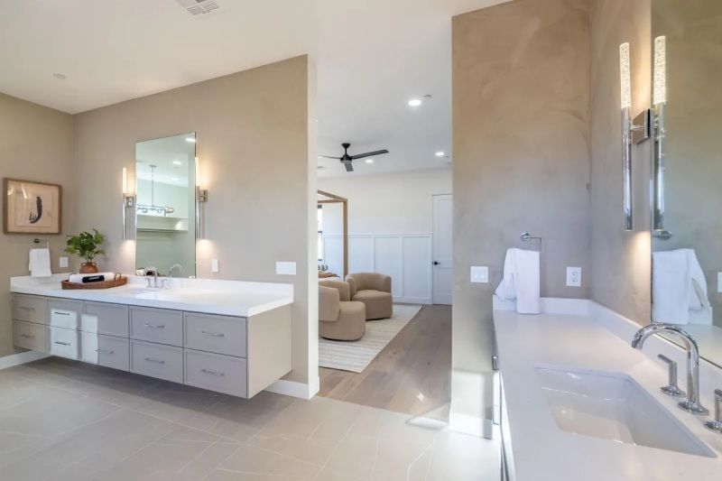 Modern bathroom with dual sinks, floating vanity, and a view into a living area.