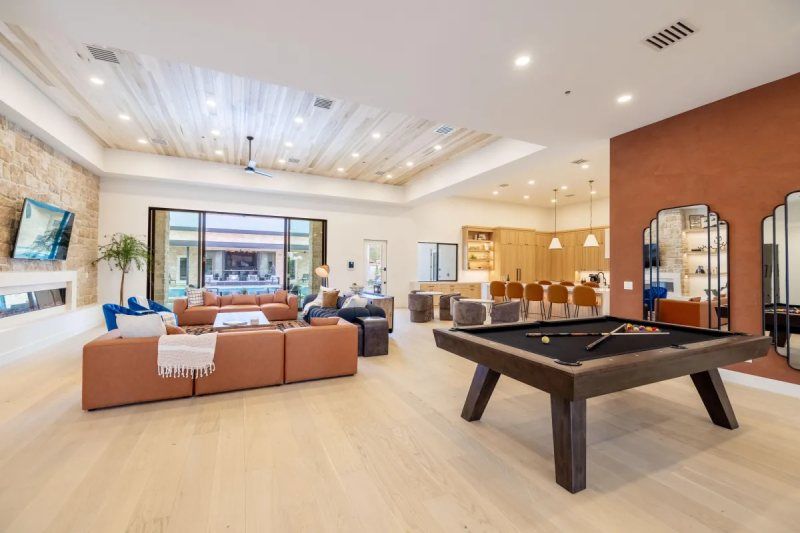 Spacious game room with a pool table, large leather sofa, and a bar area.